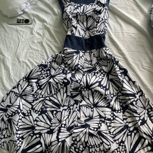 Klänning  - Marinblå mönstrad klänning med band runt midjan och dragkedja vid ryggen 