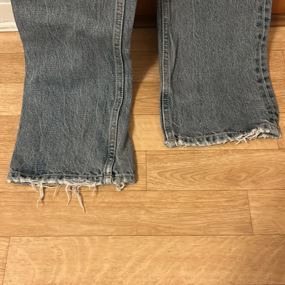 Säljer ett par klassiska blå jeans med en cool vintage-look. De har en hög midja och raka ben med fransiga kanter för en avslappnad stil. Perfekta för vardagsbruk och kan stylas med nästan vad som helst. De har knappar framtill och är i ett välanvänt skick, vilket ger dem en extra charm.. Jeans & Byxor.