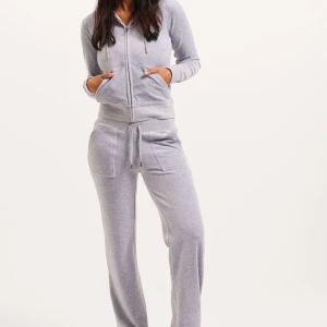 Grå hoodie och byxor från Juicy Couture - Säljer en supermysig grå hoodie och matchande byxor från Juicy Couture i storlek XXS. Hoodien har dragkedja och fickor fram, och byxorna har en bekväm passform med fickor. Perfekt för en chill dag hemma eller en avslappnad promenad. Setet är i bra skick och väldigt bekvämt! 💖