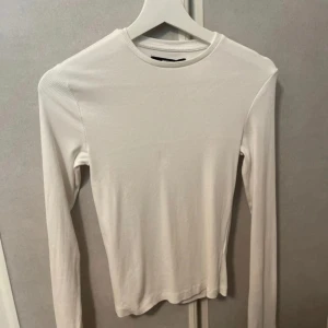 Vit topp - Vit långarmad topp i ribbat material.