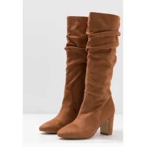 Bruna stövlar med blockklack - Snygga bruna stövlar i skinnimitation med en bekväm blockklack. De har en rund tå och stängs med dragkedja på sidan. Perfekta för höst och vinter med sitt tunna foder och slitstarka thunit-sula. Enfärgad design med elastisk isättning för extra komfort. Köpta för 739kr