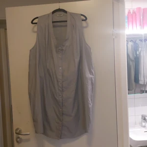 Grå ärmlös skjorta från MTWTFSS - Säljer en stilren och luftig grå ärmlös skjorta från MTWTFSS i storlek medium/large. Skjortan har en avslappnad passform med knappar framtill och en djup v-ringning. Perfekt för en casual look eller sommarens varma dagar!