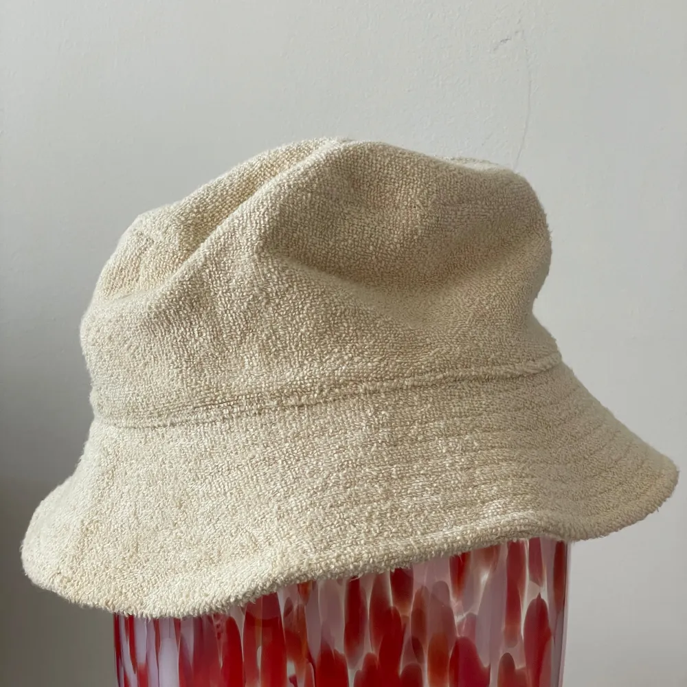 L/58 Ljus beige Frotté fiskarhatt   https://www.arket.com/sv_se/women/accessories/product.towelling-bucket-hat-beige.1065885001.html. Accessoarer.