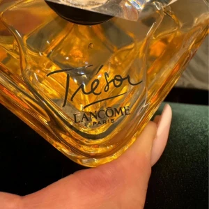 Lancôme Trésor Parfym - Säljer en elegant och lyxig parfym från Lancôme, Trésor. Flaskan är vackert designad med en fyrkantig form och en klar kristalliknande kork. Parfymen har en gyllene färg som ger en känsla av exklusivitet. Perfekt för speciella tillfällen eller som en fin present. Köp direkt eller ge prisförslag 💛