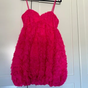 Rosa klänning - Denna chockrosa ros klänningen från Bershka är aldrig använd med prislappen kvar. Den har reglerbara band på sig samt dragkedja i bak. Stretchig i storleken.  Mini klänning