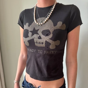 Svart t-shirt med dödskalletryck - Cool svart t-shirt med ett stort dödskalletryck med texten 'READY TO PARTY' på framsidan. T-shirten är kortärmad och croppad, väldigt edgy💕. tröjan är orginalt en barn tröja som jag använde som en babytee men skulle säga toppen blir en tajt xs💗