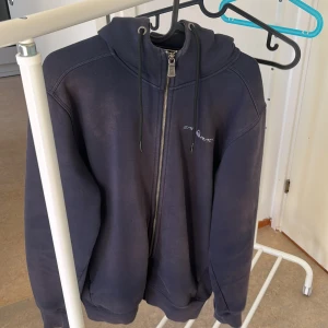 Mörkblå hoodie från Sail Racing - Säljer en mörkblå hoodie från Sail Racing i storlek L. Den har en dragkedja framtill och en justerbar huva med snören. På baksidan av huvan finns en liten logga. Perfekt för höst och vinter, supermysig och varm!