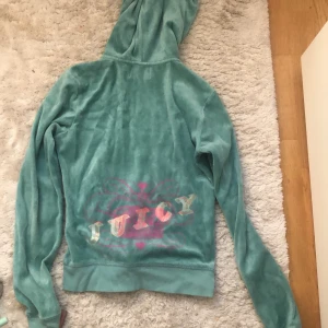 Grön hoodie från Juicy Couture - grön hoodie från Juicy Couture i storlek S. Den har en dragkedja framtill och en luva. På baksidan finns en färgglad Juicy-logga. Hoodien har en liten fläck på ärmen och ena fickan är lite sönder💚 ge gärna pris förslag💕