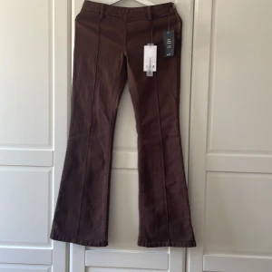 Lågmidjade bootcutjeans i strl 36 från NaKD  - Bruna lågmidjade jeans med bootcut i strl 36, helt oanvända med lapparna kvar. Innerbenslängd 80 cm.