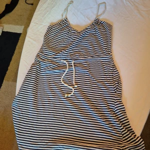 Randig klänning från H&M - Säljer en superfin randig klänning från H&M i storlek XS. Klänningen är ärmlös med smala axelband och har ett knytband i midjan för en snygg passform. Perfekt för sommaren och passar både till vardags och fest. Materialet känns mjukt och skönt mot huden.