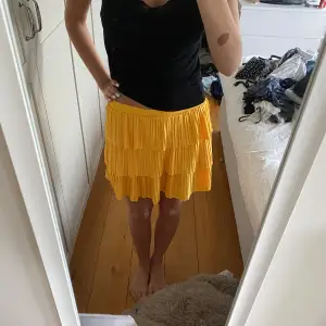 Säljer en superfin gul volangkjol som är perfekt för sommaren! Kjolen är kort och har flera lager av volanger som ger en härlig och lekfull look. Den är i nyskick och passar perfekt till både vardag och fest. Materialet känns lätt och luftigt, vilket gör den bekväm att bära hela dagen.