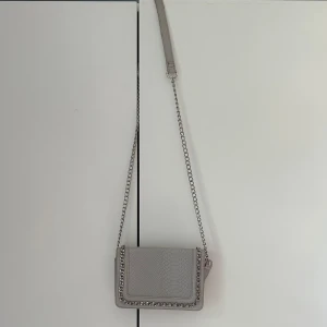 Grå handväska - Säljer denna super fina väskan, bredd: 21cm längd: 15cm djup: 5cm 💓 har lite slitningar på axelbandet💕 pris kan absolut diskuteras!