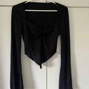 Svart långärmad topp med knutdetalj - Säljer en svart långärmad topp med en snygg knutdetalj framtill. 