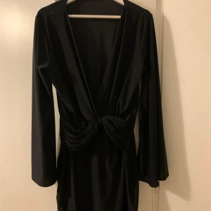 Kort klänning från Nelly - Svart kort klänning med djup urringning. Har vriden detalj vid midjan och vida ärmar. Är i runt och luftigt material. Är inte genomskinlig. Köparen står för frakt 💕