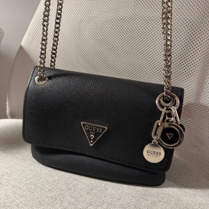 Guess väska - Varsamt använd Guess väska med tre fack varav ett med dragkedja. Går att ha som handväska och axelbandsväska. 