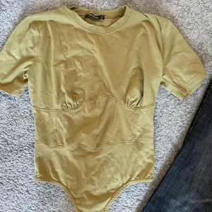 Sthlm stil korsett tshirt body - En jättesnygg militärgrön korsett tshirt-body? Knappt använd. Går bra att ha som vanlig tshirt bara att vika upp det andra tyget och dra på ett par jeans! Köpare står för ev. frakt men möter gärna upp i centrala sthlm💗💞