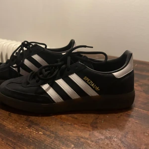 Svarta Adidas Spezial sneakers - Säljer ett par snygga och klassiska Adidas Spezial sneakers i svart med vita ränder. Skorna har en stilren design med snörning och en bekväm passform. Perfekta för både vardag och fest!                                                                   Använda enbart 1 gång!