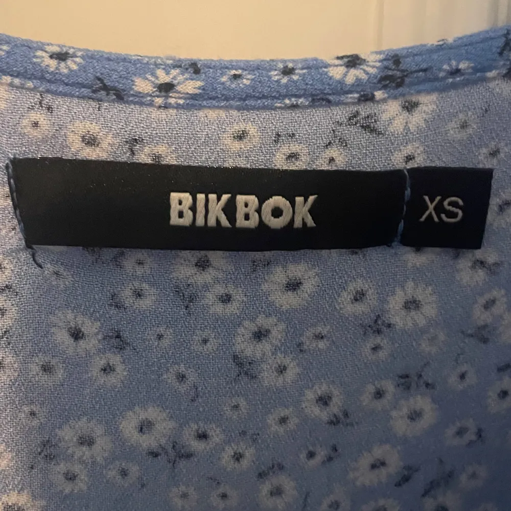 Säljer en superfin blå topp från BikBok i storlek XS. Den har ett sött blommigt mönster och korta puffärmar. Toppen är perfekt för vår och sommar och har en v-ringad design. Den är endast använd ett fåtal gånger och är i ett mycket fint skick 💕💕. Toppar.