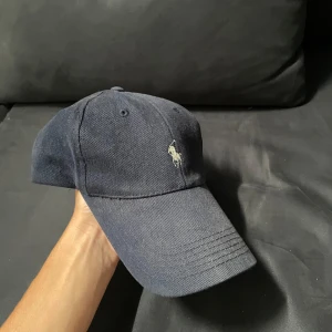 Ralph Lauren Keps - Säljer nu denna riktigt fina Ralph Lauren keps i mörkblå, den är one size så den passar alla och alla outfits. Om du har några frågor så är det bara att ställa.
