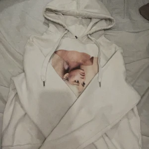 Vit hoodie med Ariana Grande motiv - Säljer en superfin vit hoodie från Ariana Grandes Sweetener-kollektion. Den har ett stort tryck av Ariana på framsidan och texten 'Sweetener' på baksidan. Perfekt för alla fans! Den är i storlek XS och är riktigt mysig och bekväm. Jag har använt ca 4-5 gånger.