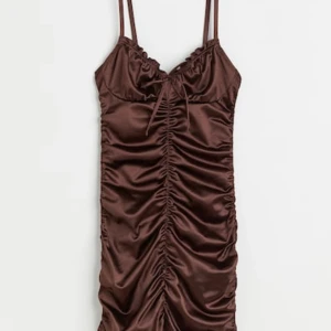 Oanvänd H&M klänning - Denna superfina bruna satin klämningen från hm köptes förra året, har aldrig använt den samt så är prislappen kvar. (Köparen står för frakt)