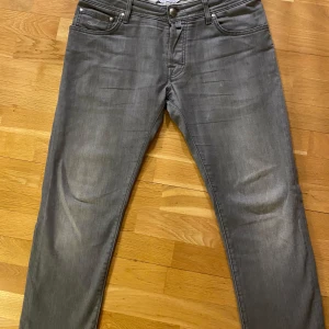 Grå jeans från Jacob Cohen w 33 l 30 - Snygga grå jeans från Jacob Cohen med klassisk femficksdesign och knappgylf. Tillverkade av exklusiva tyger med italienskt hantverk. Perfekta för en stilren look.