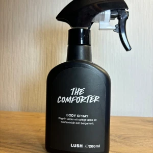 The Comforter Body Spray från Lush - Ca 150ml kvar i flaska av The Comforter Body Spray från Lush. Doften är en härlig blandning av svartvinbär och bergamott, perfekt för att svepa in sig i en saftig och fruktig arom.