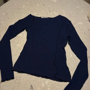 Mörkblå långärmad topp från Weekday - Säljer en stilren mörkblå långärmad topp från Weekday. Perfekt för en avslappnad look med sin enkla design och mjuka material. Liten slits ner till. Passar bra till både jeans och kjol.