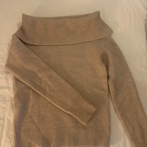 Beige stickad tröja från Amisu - Mysig beige stickad tröja från Amisu i storlek XS. Den har en offshoulder-design med långa ärmar och ribbade kanter. Perfekt för höst och vinter för en stilren och bekväm look. Passar både till vardags och lite finare tillfällen.