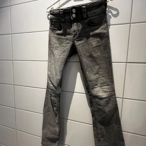 Grå jeans med låg midja - Säljer ett par grå jeans i bra skick. De har en snygg låg midja och en klassisk femficksdesign. Perfekta för vardagsbruk och kan enkelt matchas med olika toppar. Passformen är tight och materialet är slitstarkt, vilket gör dem både bekväma och hållbara.
