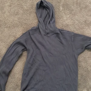 Mörkblå ribbad hoodie från lager 157 - Säljer en mörkgrå ribbad hoodie från lager 157 i bra skick. Den har en skön passform med långa ärmar och en praktisk huva. Perfekt för kyliga dagar när du vill vara både bekväm och stilren. Passar till både vardag och avslappnade tillfällen. Ej använd