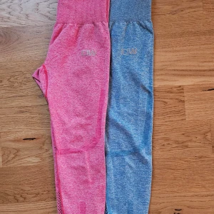 Rosa och blå träningstights från ICIW - Säljer två par snygga träningstights från ICIW i rosa och blått. De är i mycket bra skick och perfekta för att hålla saker på plats vid träning. Materialet är stretchigt och bekvämt med snygga meshdetaljer längs benen för extra ventilation. Perfekta för gymmet, löpning eller yoga!