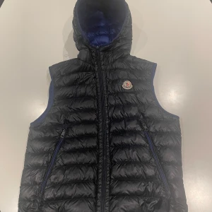 Svart/blå dunväst från Moncler - Snygg och ovanlig dunväst från moncler.    Storlek 2 vilket motsvarar S/M. Västen är i väldigt bra skick.    Nypris runt 5500kr                                                                    Hör av er vid frågor👍 !Kvitto Finns!