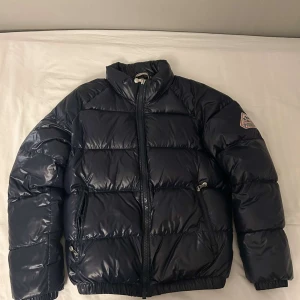 Pyrenex jacka  - Säljer en snygg mörkblå dunjacka från Pyrenex i storlek M. Jackan är perfekt för vintern. Den har en klassisk stil och knappt använd och i nyskick.  Köpt på NK. Perfekt för att hålla dig varm och stilren under kalla dagar! Tveka inte på att höra av er!