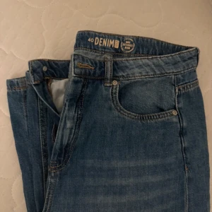 Blå jeans från Denim - Säljer ett par klassiska blå jeans från Denim. De har en normal passform och är tillverkade i hållbart denimtyg. Perfekta för en avslappnad stil. Breda byxor.