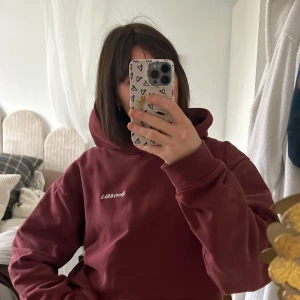 Vinröd hoodie från Sporty & Rich - Säljer en snygg vinröd hoodie från Sporty & Rich. Den har en klassisk design med en bekväm huva och tryck på bröstet. Sparsamt använd, endast ett litet hål på magen som knappt syns, de bild! 🙌🏼