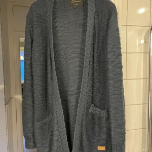 Blå stickad kofta - Stickad kofta med långa ärmar och två praktiska fickor framtill. Perfekt för kyliga dagar och att mysa i hemma. Enkel och stilren design som passar till det mesta.