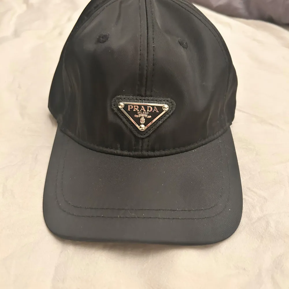 Snygg svart keps från Prada med justerbar rem baktill. Kepsen har en broderad logotyp framtill och är tillverkad i ett lätt och bekvämt material. Perfekt för en stilren look.. Asusteet.