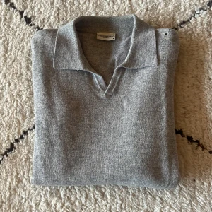 Grå tröja från John Henric - Skit skön långärmad piké från John Henric. Mycket bra skick, knappt använd. Dock ett litet hål, se bild två. Därav det enormt låga priset (nypriset är 1000kr). Kashmir/ull blandning.