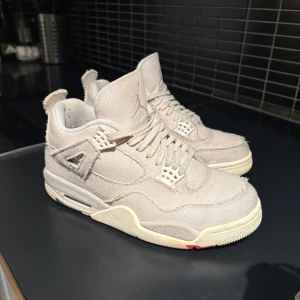 Air Jordan 4 Retro 'Blank Canvas' - Snygga Air Jordan 4 Retro 'Blank Canvas' sneakers i en stilren beige färg. Skorna har en unik design med färgglada detaljer på sulan och klassisk snörning. Perfekta för dig som vill ha en stilren look. Priset är förhandlingsbart