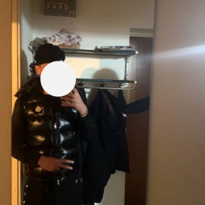 Svart dunväst från Moncler - Säljer en snygg svart dunväst från Moncler i mycket bra skick. Västen har en glansig finish och är perfekt för höst och vinter. Den har en dragkedja framtill och praktiska fickor med dragkedjor. Perfekt för att hålla sig varm och stilren under kyliga dagar.