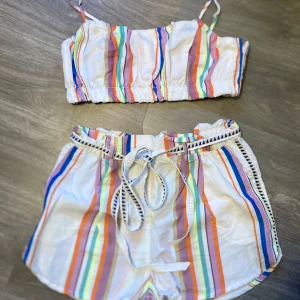 Set topp och shorts strl L - Ett set med en kort topp och tillhörande shorts. Båda är i storlek L.  Från H&M. Resår i midjan på shortsen, avtagbart skärp.  Överdelen har dragkedja i sidan och justerbara axelband. Mycket fint skick.