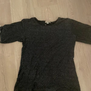 Svart glittrig topp från Odd Molly - Säljer en svart glittrig topp. Toppen har korta ärmar och en rund halsringning. Perfekt för att lägga till lite glitter i vardagen. 🖤✨