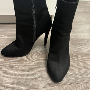 Svarta klackar  - Snygga svarta klackar i mocka med spetsig tå och dragkedja på sidan. Perfekta för höst och vinter, dessa klackar har en elegant klack som ger en stilren look. Passar både till vardags och festliga tillfällen.