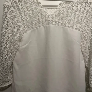 Vit spetsblus från Stockh LM - Säljer en elegant vit blus från Stockh LM i storlek 36. Klänningen har vackra spetsdetaljer och trekvartsärmar! Knappen i nacken saknas, men utöver det är skicket superbra🤍