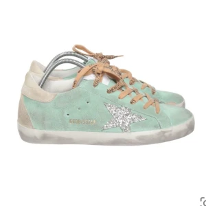 Golden goose skor - Snygga mintgröna sneakers från Golden Goose med en glittrig stjärna på sidan. De har orange/beiga smörning där det står golden goose, inte använda många gånger! Är själv storlek 37 och de passar mig