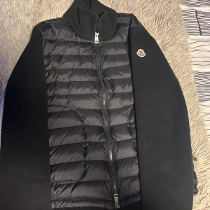 Moncler Cardigan - En svart moncler cardigan. Den ser lite mörkblå ut på bilden men den är svart. Den har inga skador eller smuts och är äkta! Digitalt kvitto följer med👍