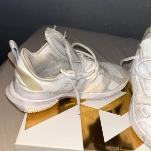 Jordan Why Not Zero.4 (GS) i vitt - Säljer ett par Jordan Why Not Zero.4 (GS) sneakers i vitt med metallic detaljer. De är i bra skick och perfekta för både vardag och träning. Skorna har en snygg design med snörning och en bekväm passform. Perfekta för dig som vill ha stil och komfort i ett!