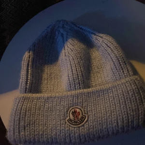 Baby blå stickad mössa från Moncler - Snygg grå stickad mössa från Moncler med broderad logotyp framtill. Perfekt för kyliga dagar och ger en stilren look.