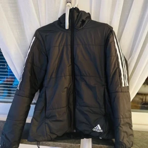 Grå adidas jacka - En vanlig grå adidas dunjacka. Fortfarande i bra skick och har används under en årstid period (hösten) väldigt mjuk och skön material. Håller dig varm och passar helt perfekt till hösten elr under våren när de känns lite kallt. 